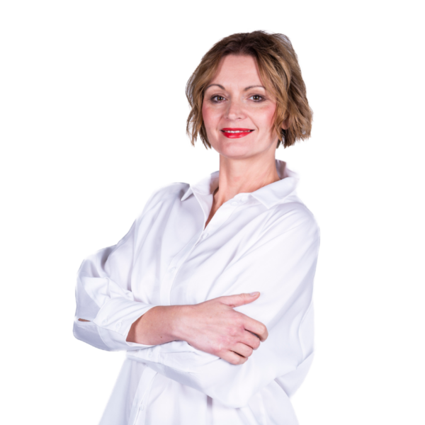 Portret uśmiechniętej kobiety w białej koszuli, stojącej ze skrzyżowanymi rękami na jasnym tle.