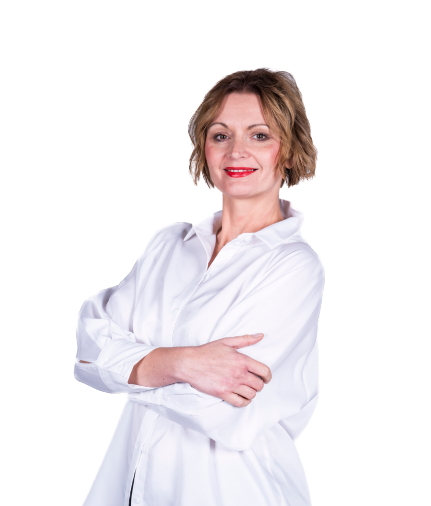 Portret uśmiechniętej kobiety w białej koszuli, stojącej ze skrzyżowanymi rękami na jasnym tle.