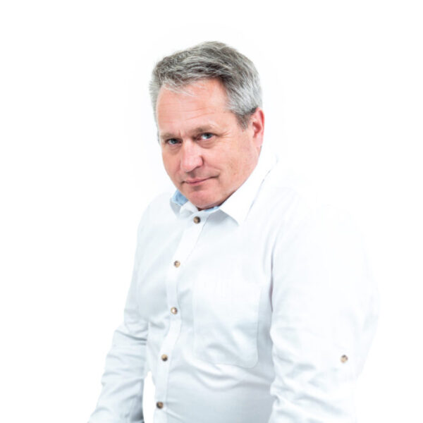 Portret mężczyzny z krótkimi siwymi włosami, ubranego w jasną koszulę, na białym tle.